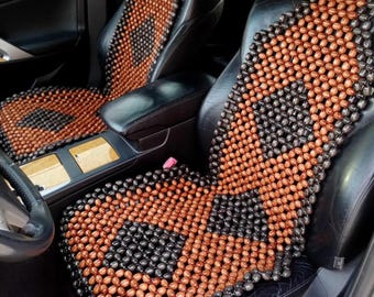 May include: A brown and black wooden bead car seat cushion. The cushion is made of small, round beads that are woven together in a grid pattern. The cushion is designed to provide comfort and support while driving.