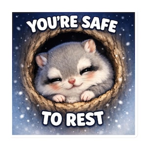 Op de afbeelding: Een sticker met een schattig, lachend, grijs en wit dier met roze wangen, genesteld in een boomholte. De tekst "YOU'RE SAFE TO REST" staat in het wit boven en onder het dier, tegen een blauwe achtergrond met vallende sneeuw.