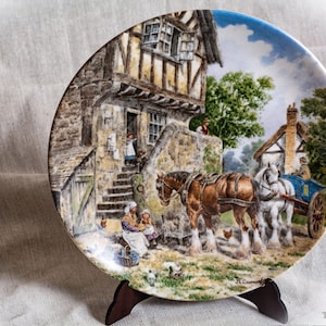 May include: A white ceramic mug with a black handle and the text "But First, Coffee" in a bold, black font. The mug is set against a blurred background, suggesting a cosy setting.