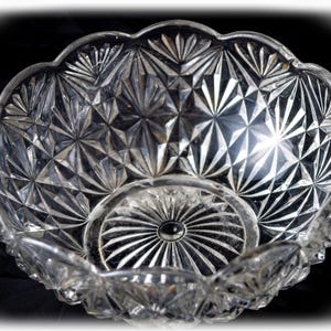 Puede incluir: Un cuenco de cristal transparente con un patrón geométrico de estrella prensado en las superficies interior y exterior. El cuenco tiene un borde festoneado y una base circular con un diseño radiante. El texto Torch a Talon es visible.