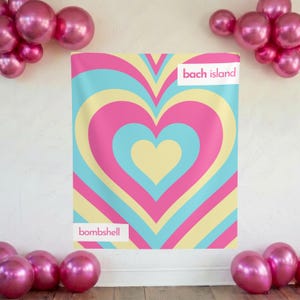 May include: A rectangular fabric backdrop featuring a repeating concentric heart pattern in shades of pink, light blue, and pale yellow. The text "bach island" appears in the top right corner and "bombshell" in the bottom left, surrounded by pink balloons.