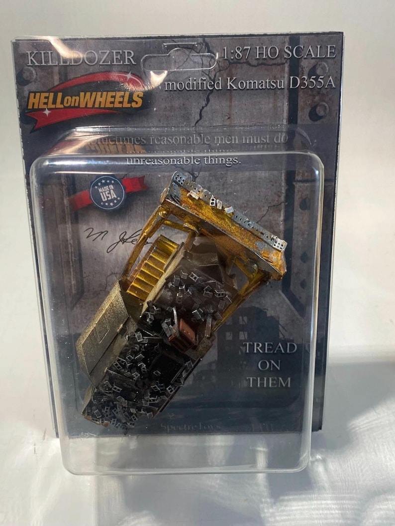 May include: A 1:87 HO scale model of the Killdozer, a modified Komatsu D355A bulldozer. The model is in a clear plastic package with the "HELLonWHEELS" logo and the text "TREAD ON THEM". The model is made in the USA.