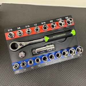 May include: A black and red socket set with a variety of sockets, a ratchet, and an extension bar. The sockets are labeled with sizes from 5/16 to 3/4 inches. The ratchet handle is black with a green grip, and the brand name "PITTSBURGH" is printed on the handle.