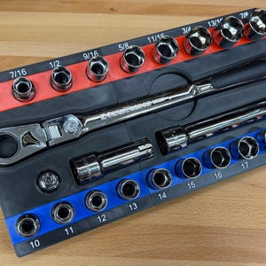 May include: A mechanic's tool set featuring a ratchet wrench and various sockets. The sockets are arranged in a black tray with red and blue accents, labeled with inch measurements. The set includes a variety of sizes for different applications.