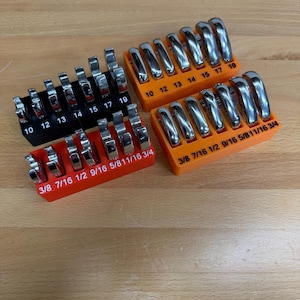May include: Four sets of chrome wrenches in orange and black holders. Each holder is labeled with wrench sizes, including 3/8, 7/16, 1/2, 9/16, 5/8, 11/16, and 3/4 inch sizes, and metric sizes 10, 12, 13, 14, 15, 17, and 19.