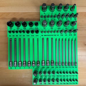 May include: A collection of various hex and Torx bit sockets and extensions, neatly organized in green holders. The set includes a range of sizes, from E4 to E24, and T8 to T60, ideal for automotive or mechanical work.