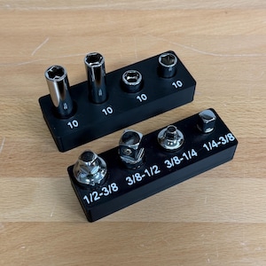 May include: Two black socket organizers with various sockets and nuts. The top organizer has four sockets labeled "10". The bottom organizer has four nuts labeled "1/2-3/8", "3/8-1/2", "3/8-1/4", and "1/4-3/8".