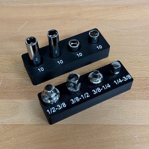May include: Two black socket organizers with various sockets. The top organizer has four sockets labeled "10". The bottom organizer has four sockets labeled "1/2-3/8", "3/8-1/2", "3/8-1/4", and "1/4-3/8".