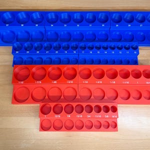 May include: Blue and red plastic socket organizers. The blue organizers have numbered slots, while the red ones display fractional inch sizes from 9/16 to 1-1/2 inches. Ideal for tool organization.