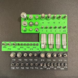 May include: A set of tools, including sockets and bits, arranged on green and black holders. The tools are various sizes and shapes, with measurements in inches and fractions of an inch.