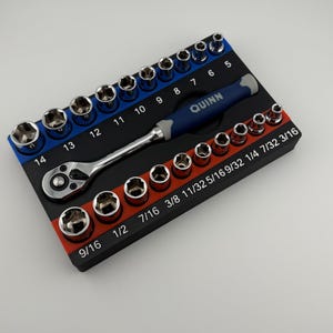 May include: A black and red socket wrench set with a blue and black handle. The set includes a variety of sizes, including 9/16, 1/2, 7/16, 3/8, 11/32, 5/16, 9/32, 1/4, 7/32, and 3/16. The set also includes a 14, 13, 12, 11, 10, 9, 8, 7, 6, and 5 socket wrench. The handle has the word "QUINN" printed on it.