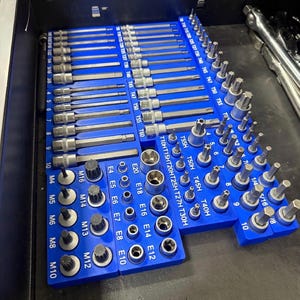 May include: A blue tool organizer filled with various metal bits and sockets. The organizer has labels with sizes and types, including T10HT15HT20HT25H, T27H, T30H, T40H, T45H, T50H, and T55H. The tools are arranged neatly.