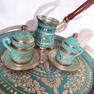 Könnte beinhalten: Ein türkisfarbenes und goldenes türkisches Kaffee-Set mit einem Tablett, zwei Tassen und einer Kanne mit einem Holzgriff.