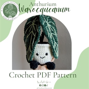 Op de afbeelding: Een haakpatroon van een Anthurium warocqueanum plant met twee lange, donkergroene fluwelen bladeren met lichtgroene nerven, bevestigd aan een witte pot met een lachend gezicht en zwarte ogen, met de tekst Anthurium warocqueanum en Crochet PDF Pattern.
