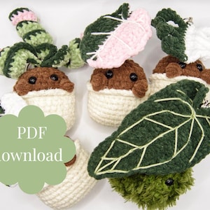 May include: A collection of handmade crochet plant-themed keychains. The keychains feature a variety of designs, including a brown pot with a plant, and green and pink leaves. The text "PDF download" is visible on a green cloud-shaped graphic.