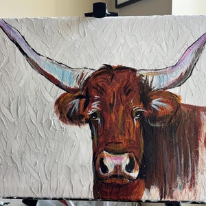 May include: An original oil painting of a longhorn steer. The steer is painted with shades of brown and white, with large horns that are white, blue, and purple. The background is a textured white.
