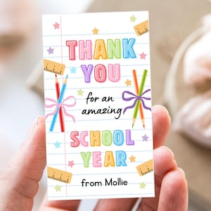 K&ouml;nnte beinhalten: Eine rechteckige Dankeskarte mit dem Text "THANK YOU for an amazing SCHOOL YEAR from Mollie." Die Karte zeigt farbenfrohen Text, Bleistifte, B&auml;nder, Lineale und Sterne auf einem linierten Papierhintergrund.