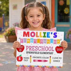 Op de afbeelding: Een wit rechthoekig bord met kleurrijke tekst en afbeeldingen met de tekst MOLLIE'S FIRST DAY OF PRESCHOOL, SPRINGFIELD ELEMENTARY, AUG 18 2025, 5 YEARS OLD, FAVORITE COLOR en I LOVE TO DANCE, voorzien van illustraties van appels en potloden.