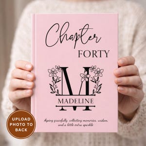 Op de afbeelding: Een roze notitieboek met de woorden "Chapter FORTY" in zwart schrift. De letter "M" is gecentreerd met bloemaccenten en de naam "Madeline" eronder. Het notitieboek heeft de tekst "Gracieus ouder worden: herinneringen verzamelen, wijsheid en een beetje extra sprankeling".