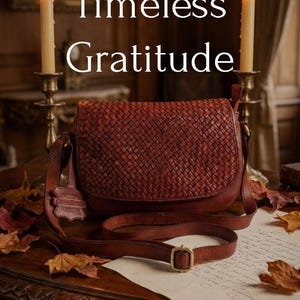 May include: A brown woven leather crossbody bag with a flap closure and an adjustable strap. The text "Gifts Woven in Timeless Gratitude" and "Honor the extraordinary women in your life this Thanksgiving with a gift of heritage" is visible.