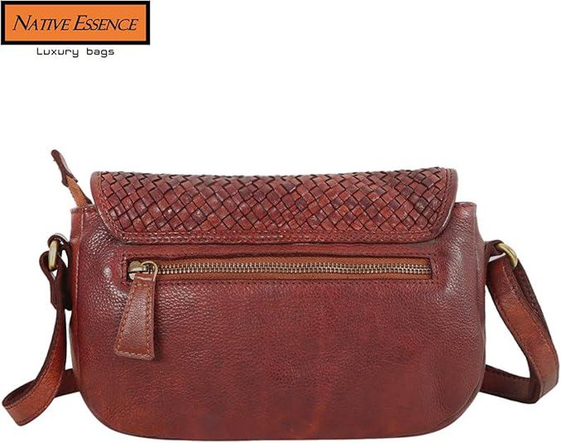 May include: A dark red leather crossbody bag featuring a woven texture on the top flap and a zippered pocket on the front. The bag includes a shoulder strap attached with brass-toned metal hardware. The text Native Essence Luxury bags is visible.