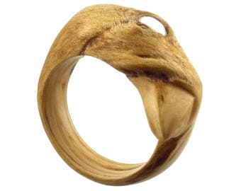 May include: A wooden ring with a carved design resembling a bird's head. The ring has a white stone set in the eye of the bird.