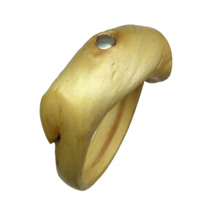 May include: A wooden ring with a silver inlay. The ring is made of natural wood and has a unique, organic shape.
