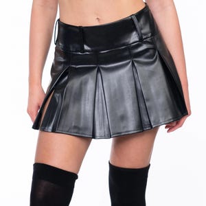 May include: A black faux leather mini skirt with pleats and a high waist.