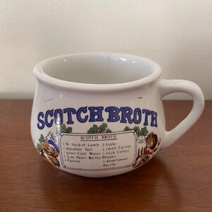 May include: White ceramic mug with a blue and white design that says "Scotch Broth". The mug has a recipe for Scotch Broth printed on the side.
