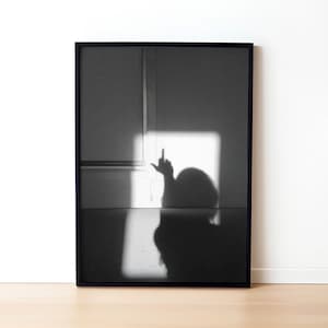 以下が含まれることがあります： 手でお粗末なジェスチャーをしている人の影の白黒写真。影は白い壁に映し出されています。