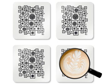 May include: Set of four square white coasters with a black geometric design. One coaster holds a cup of coffee with latte art. The coasters feature a repeating pattern of squares, circles, and diamond shapes.
