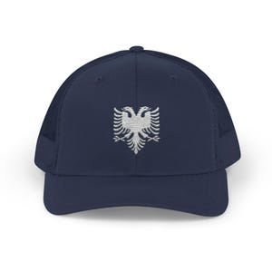 May include: Navy blue trucker hat featuring a white embroidered double-headed eagle emblem. The hat has a mesh back for breathability and a curved brim. A stylish accessory for casual wear.
