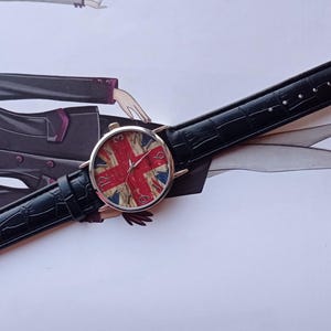 New wristwatch featuring the Union Jack (British flag) on the dial, with a black faux leather strap and silver buckle. Unused quartz timepiece, stylish and perfect for fans of British culture or punk fashion.