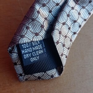 Vintage BAGOZZA MILANO necktie made in Italy from 100% pure silk. Features an elegant grey geometric pattern with a subtle sheen, representing classic Italian menswear design. This luxury tie is in great vintage condition, ideal for collectors or anyone seeking timeless formal accessories. Perfect for pairing with suits, businesswear, or dress shirts, this piece offers sophistication and heritage craftsmanship.