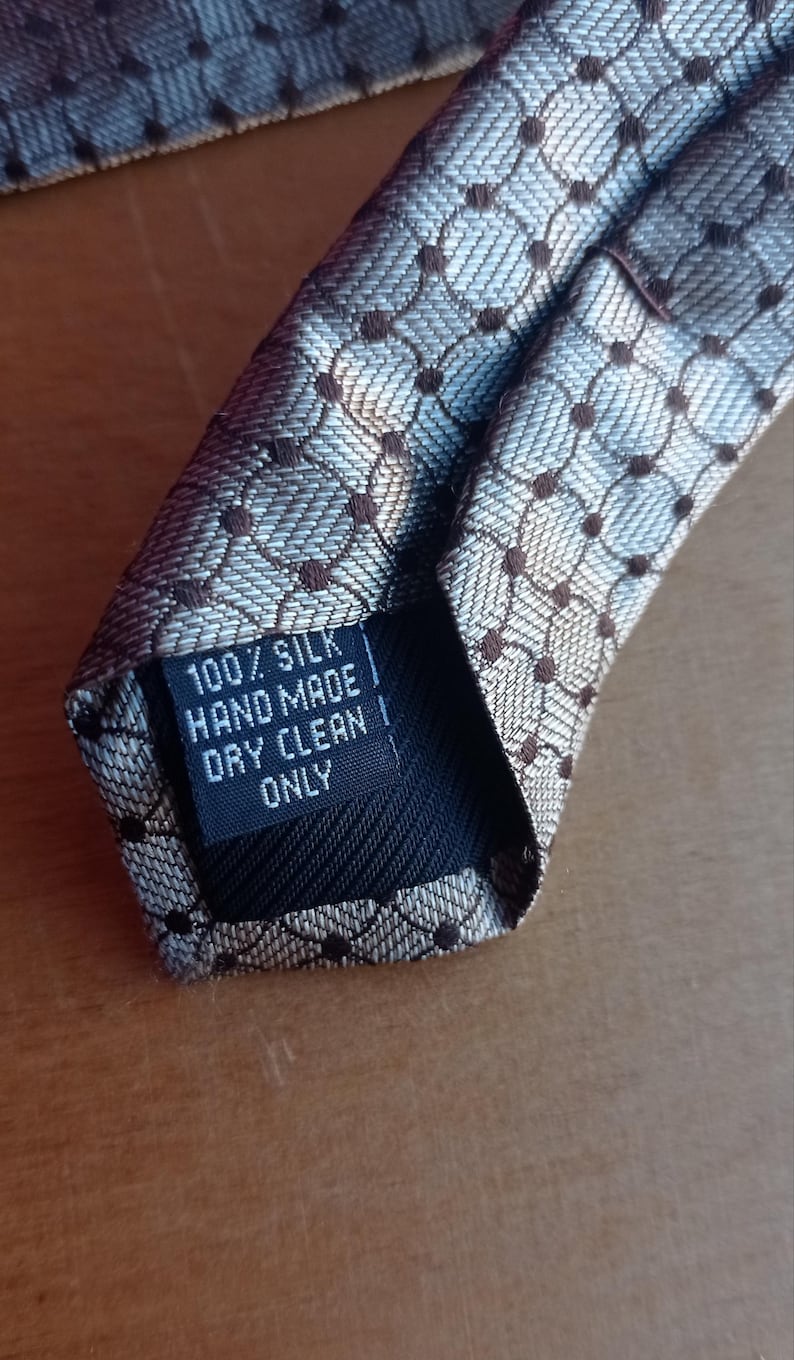 Vintage BAGOZZA MILANO necktie made in Italy from 100% pure silk. Features an elegant grey geometric pattern with a subtle sheen, representing classic Italian menswear design. This luxury tie is in great vintage condition, ideal for collectors or anyone seeking timeless formal accessories. Perfect for pairing with suits, businesswear, or dress shirts, this piece offers sophistication and heritage craftsmanship.