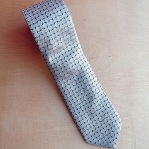 Vintage BAGOZZA MILANO necktie made in Italy from 100% pure silk. Features an elegant grey geometric pattern with a subtle sheen, representing classic Italian menswear design. This luxury tie is in great vintage condition, ideal for collectors or anyone seeking timeless formal accessories. Perfect for pairing with suits, businesswear, or dress shirts, this piece offers sophistication and heritage craftsmanship.