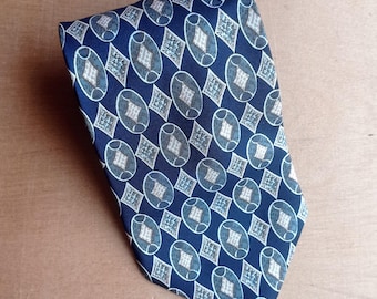 Puede incluir: Una corbata azul marino con un patrón repetitivo de óvalos y diamantes blancos y azul claro. La corbata está hecha de una tela suave y es adecuada para vestimenta formal o de negocios.