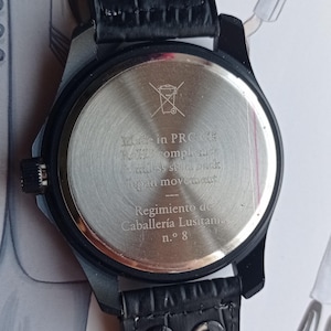 Men’s military quartz wristwatch inspired by the Spanish Army 8th Cavalry Regiment “Lusitania,” featuring a bold black dial with striking skull and crossbones emblem, a symbol of bravery, courage, and sacrifice. This collectible watch includes a precise quartz movement, durable black case, and a black leather strap with white stitching. Perfect for military history collectors, army enthusiasts, and men’s fashion lovers, this unworn timepiece represents unique heritage, bold design.
