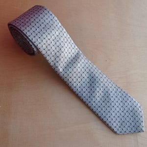 Vintage BAGOZZA MILANO necktie made in Italy from 100% pure silk. Features an elegant grey geometric pattern with a subtle sheen, representing classic Italian menswear design. This luxury tie is in great vintage condition, ideal for collectors or anyone seeking timeless formal accessories. Perfect for pairing with suits, businesswear, or dress shirts, this piece offers sophistication and heritage craftsmanship.