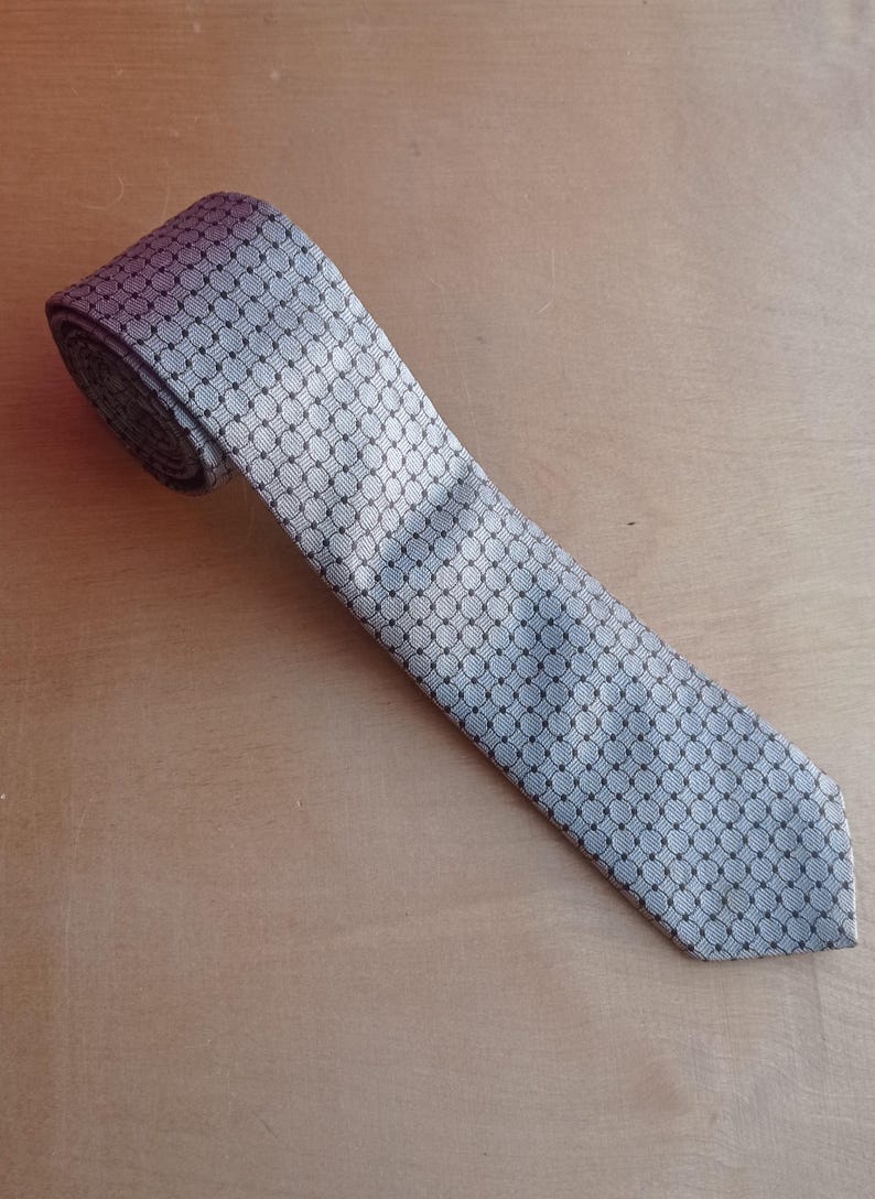 Vintage BAGOZZA MILANO necktie made in Italy from 100% pure silk. Features an elegant grey geometric pattern with a subtle sheen, representing classic Italian menswear design. This luxury tie is in great vintage condition, ideal for collectors or anyone seeking timeless formal accessories. Perfect for pairing with suits, businesswear, or dress shirts, this piece offers sophistication and heritage craftsmanship.