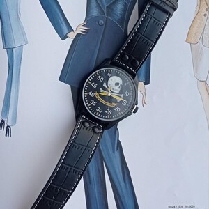 Men’s military quartz wristwatch inspired by the Spanish Army 8th Cavalry Regiment “Lusitania,” featuring a bold black dial with striking skull and crossbones emblem, a symbol of bravery, courage, and sacrifice. This collectible watch includes a precise quartz movement, durable black case, and a black leather strap with white stitching. Perfect for military history collectors, army enthusiasts, and men’s fashion lovers, this unworn timepiece represents unique heritage, bold design.