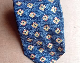 Puede incluir: Corbata azul con un patrón repetido de cuadrados amarillos con detalles rojos. La corbata tiene una textura. El diseño es clásico y adecuado para ocasiones formales. La corbata mide aproximadamente 147 cm de largo.