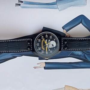 Men’s military quartz wristwatch inspired by the Spanish Army 8th Cavalry Regiment “Lusitania,” featuring a bold black dial with striking skull and crossbones emblem, a symbol of bravery, courage, and sacrifice. This collectible watch includes a precise quartz movement, durable black case, and a black leather strap with white stitching. Perfect for military history collectors, army enthusiasts, and men’s fashion lovers, this unworn timepiece represents unique heritage, bold design.