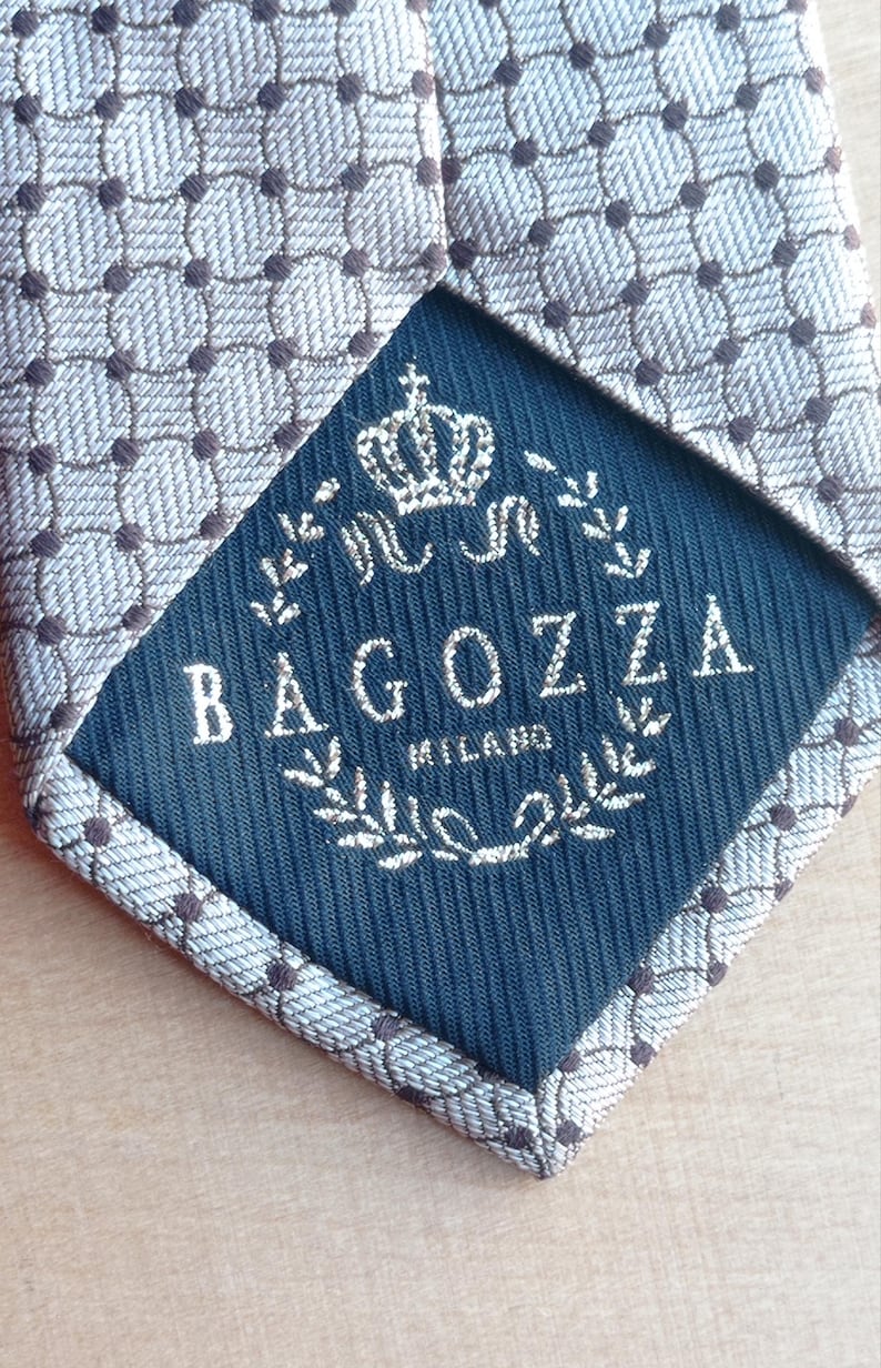 Vintage BAGOZZA MILANO necktie made in Italy from 100% pure silk. Features an elegant grey geometric pattern with a subtle sheen, representing classic Italian menswear design. This luxury tie is in great vintage condition, ideal for collectors or anyone seeking timeless formal accessories. Perfect for pairing with suits, businesswear, or dress shirts, this piece offers sophistication and heritage craftsmanship.