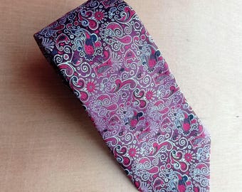 May include: A patterned necktie featuring a paisley design in shades of purple, burgundy, and white. The tie is made of a smooth fabric and is suitable for formal or business attire.