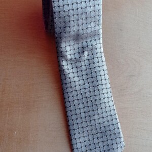 Vintage BAGOZZA MILANO necktie made in Italy from 100% pure silk. Features an elegant grey geometric pattern with a subtle sheen, representing classic Italian menswear design. This luxury tie is in great vintage condition, ideal for collectors or anyone seeking timeless formal accessories. Perfect for pairing with suits, businesswear, or dress shirts, this piece offers sophistication and heritage craftsmanship.