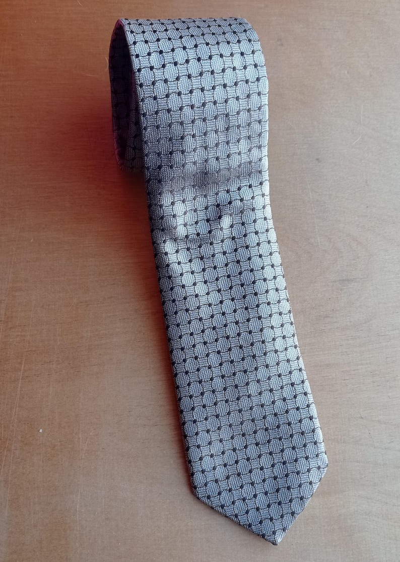 Vintage BAGOZZA MILANO necktie made in Italy from 100% pure silk. Features an elegant grey geometric pattern with a subtle sheen, representing classic Italian menswear design. This luxury tie is in great vintage condition, ideal for collectors or anyone seeking timeless formal accessories. Perfect for pairing with suits, businesswear, or dress shirts, this piece offers sophistication and heritage craftsmanship.