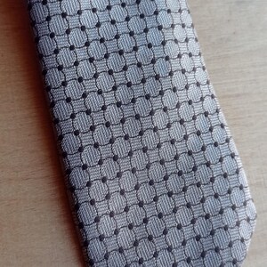 Vintage BAGOZZA MILANO necktie made in Italy from 100% pure silk. Features an elegant grey geometric pattern with a subtle sheen, representing classic Italian menswear design. This luxury tie is in great vintage condition, ideal for collectors or anyone seeking timeless formal accessories. Perfect for pairing with suits, businesswear, or dress shirts, this piece offers sophistication and heritage craftsmanship.