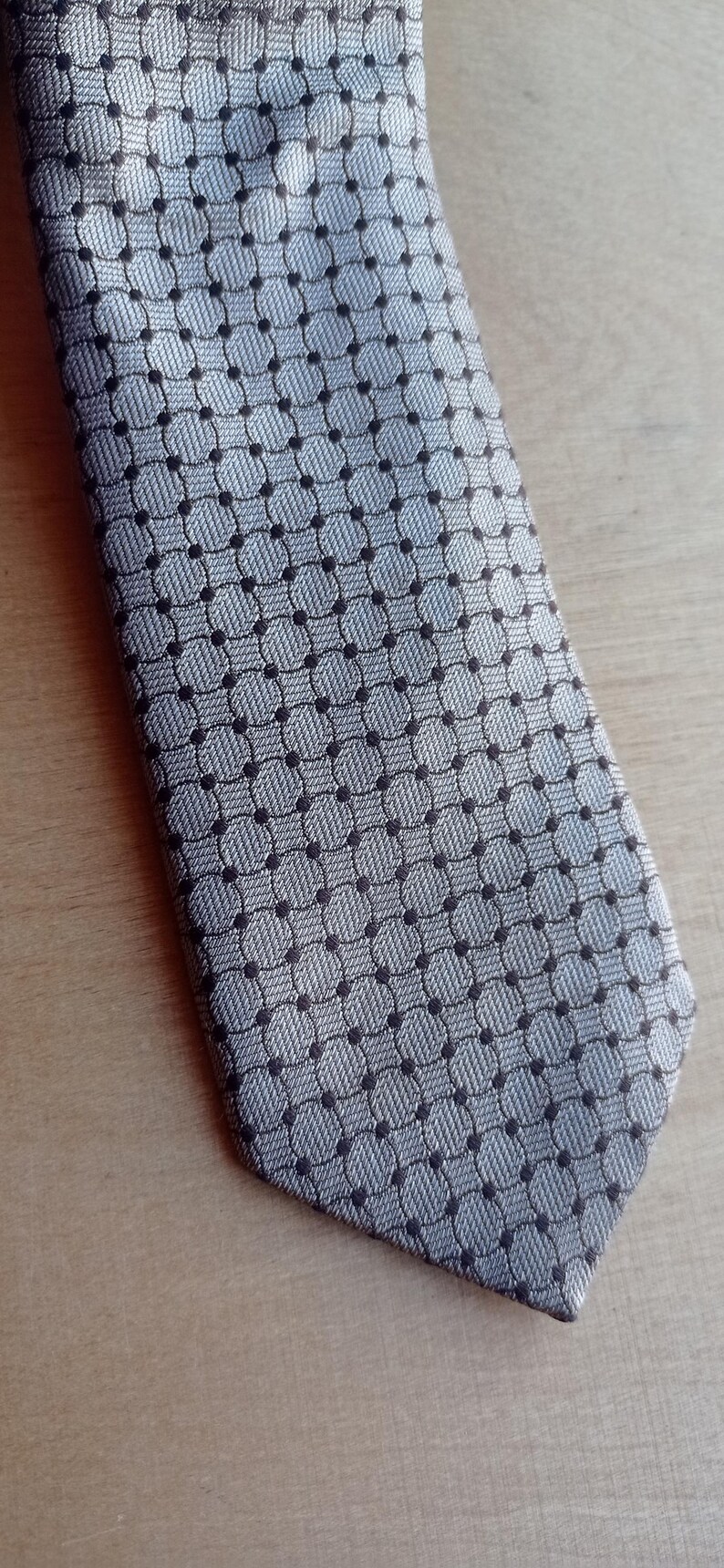 Vintage BAGOZZA MILANO necktie made in Italy from 100% pure silk. Features an elegant grey geometric pattern with a subtle sheen, representing classic Italian menswear design. This luxury tie is in great vintage condition, ideal for collectors or anyone seeking timeless formal accessories. Perfect for pairing with suits, businesswear, or dress shirts, this piece offers sophistication and heritage craftsmanship.