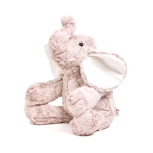 May include: A plush, light brown elephant toy with large, white-lined ears and a curled trunk. The stuffed animal is sitting with its legs crossed, and its fur has a textured appearance. The elephant's eyes are small and black.